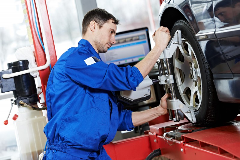 auto mechanic at wheel alignment work with spanner